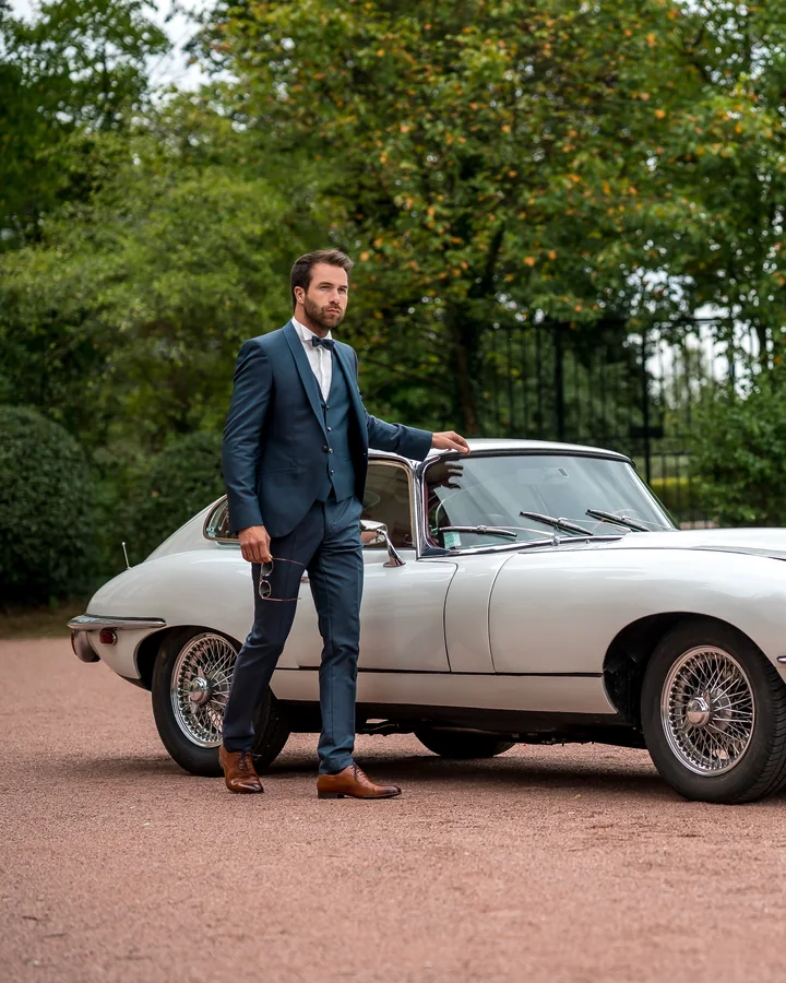 Costume de marié Camilliano Sandillon, bleu, devant une Jaguar ancienne